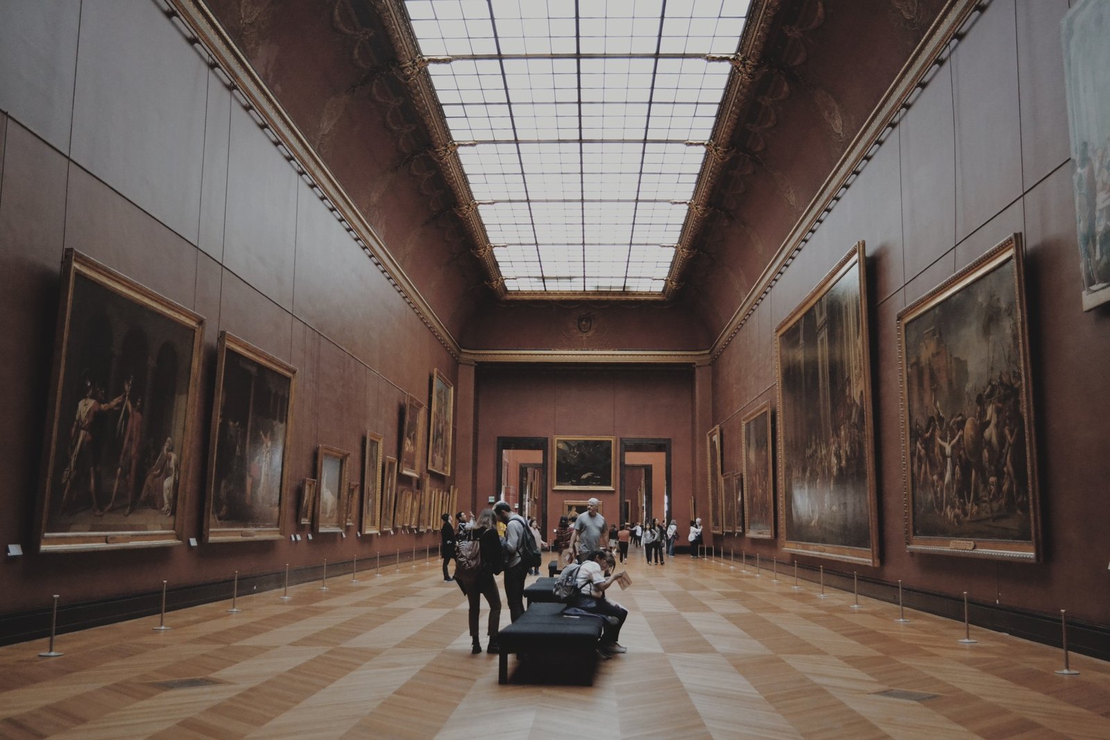 Ember — a long skylit gallery lined with large framed
                     paintings.